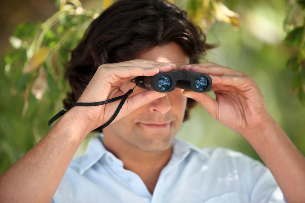 A man looking through a pair of optical instrument