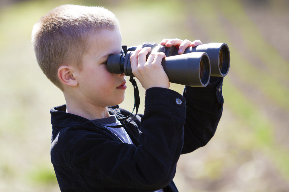 a cute little boy peeking through a black tool