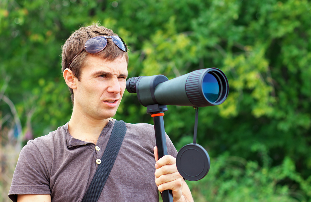 A man in the field carrying a telescope
