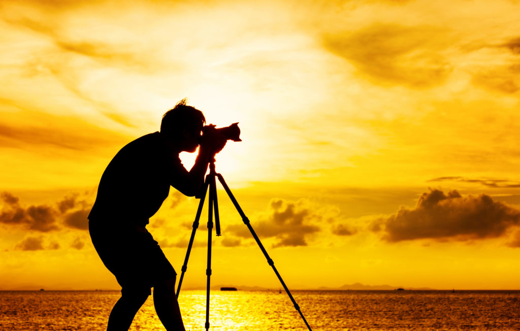 Silhouette of photographer with tripod at sunset