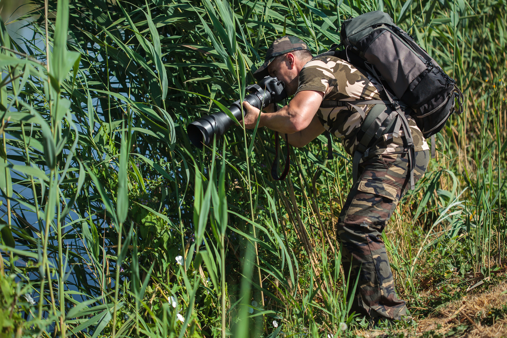 Professional nature and wildlife photographer with backpack and long lens